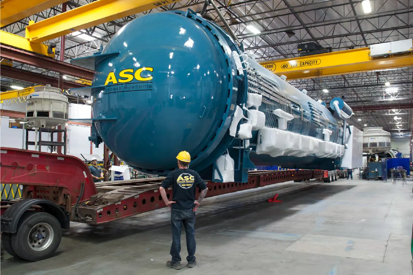 A finished ASC autoclave loaded on an oversize trailer in the Valencia plant, with an ASC technician beside it
