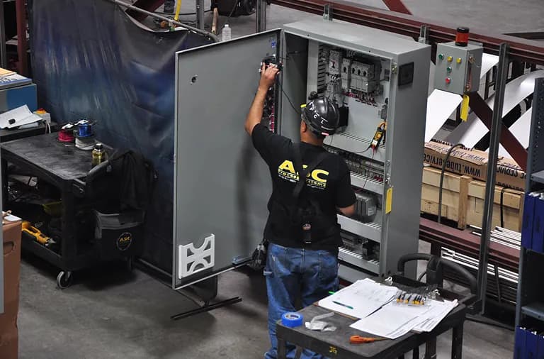 An ASC technician wiring a CPC control cabinet